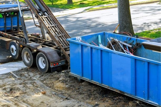 Dumpster being loaded onto a junk removal truck