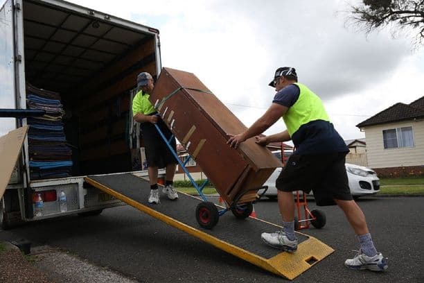 Movers using a dolly to load furniture into a truck