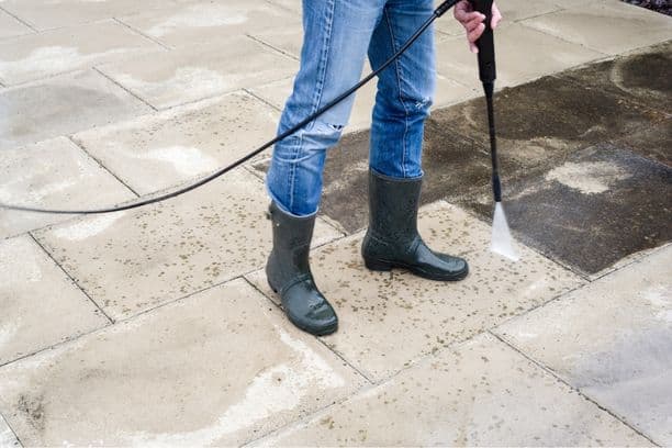 Person power washing a stone patio