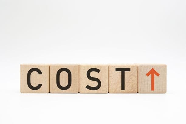 Wooden blocks spelling 'COST' with an upward arrow