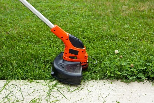 Grass trimming along a sidewalk with a string trimmer